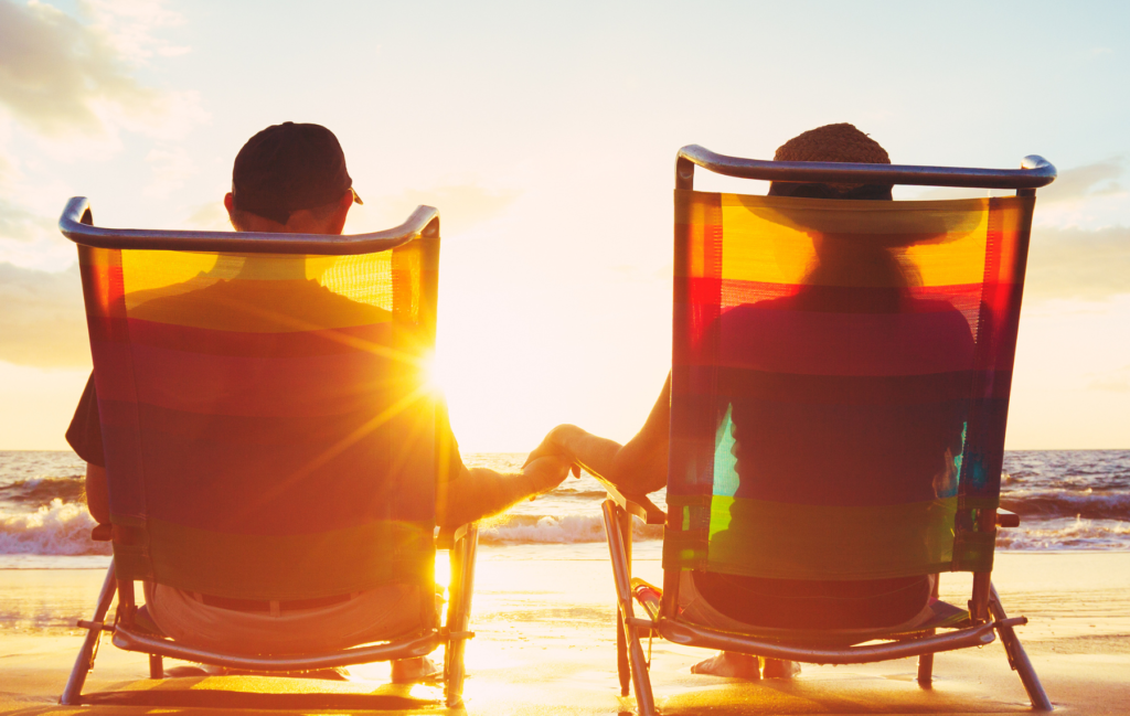 couple holding hands sitting in chair on beach overlooking the ocean