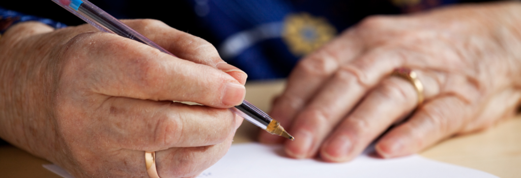 Elderly person's hands writing with pen and paper