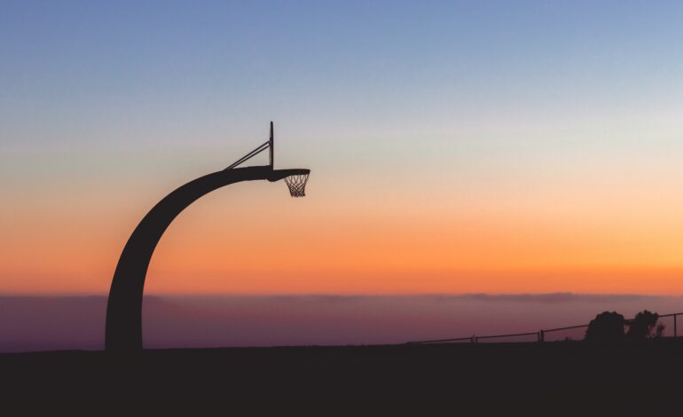 Silhouette of a basketball hoop with the beautiful view of sunset in the background