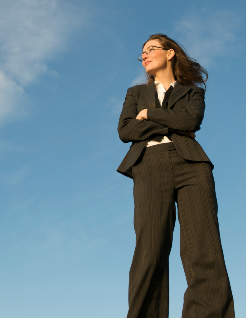 Woman in black suit with arms crossed staring into the sky