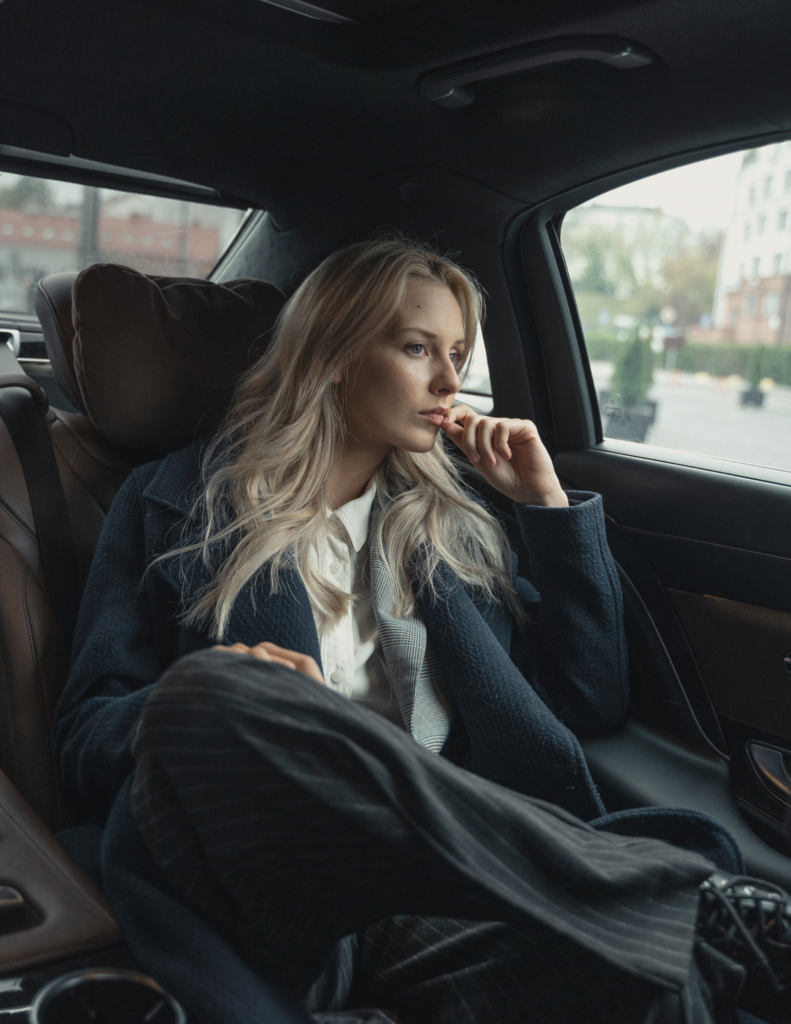 Woman in suit sitting in car thinking