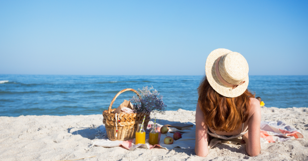 Girl sitting on the beach having a picnic