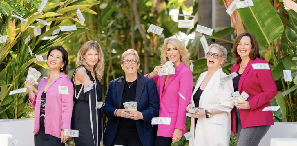 Women group together smiling and throwing cash in the air