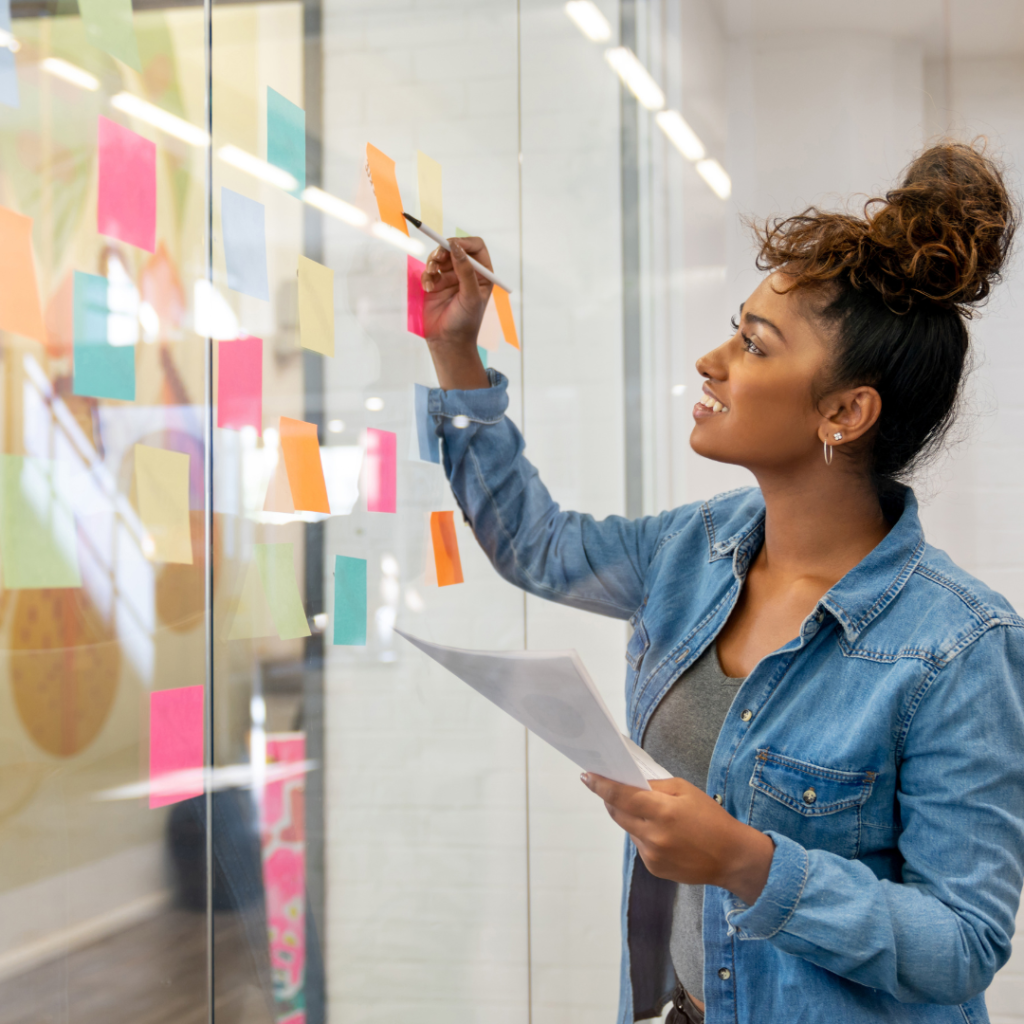 creative woman brainstorming with colorful sticky notes on glass wall