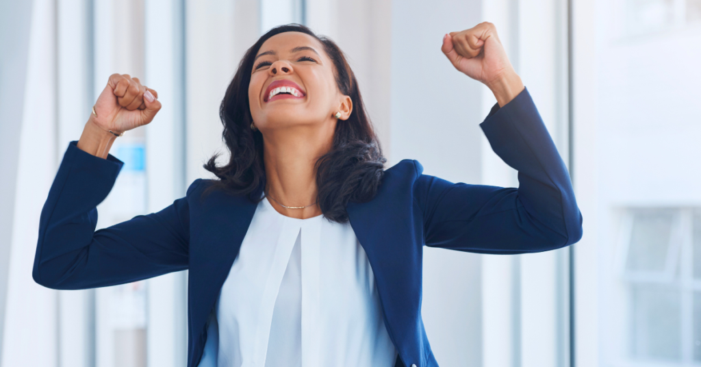 excited woman in blue business jacket with hands in the air