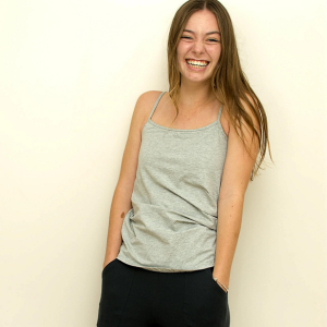 girl smiling with gray tank and hands in pocket