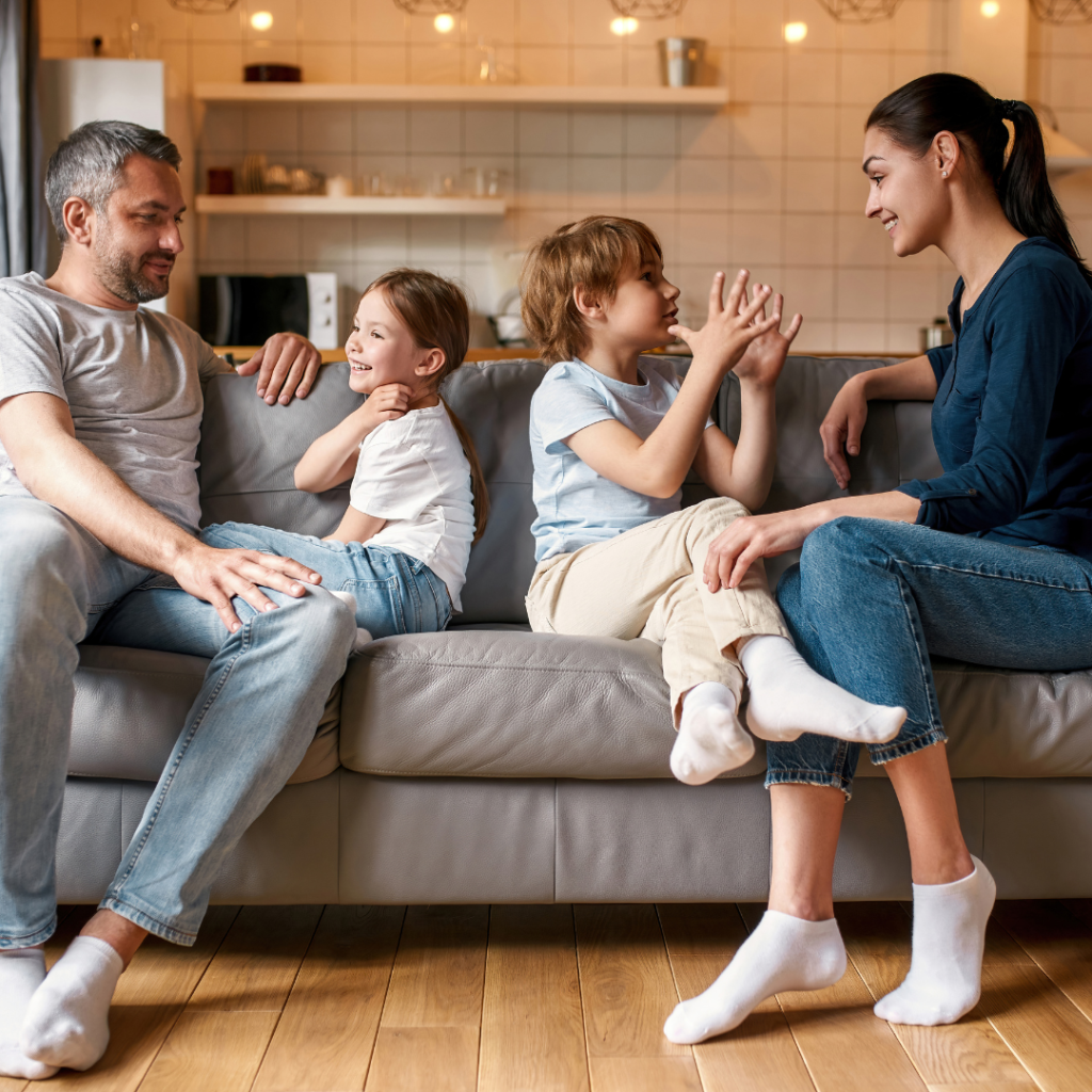 mom and dad talking to son and daughter while sitting on couch