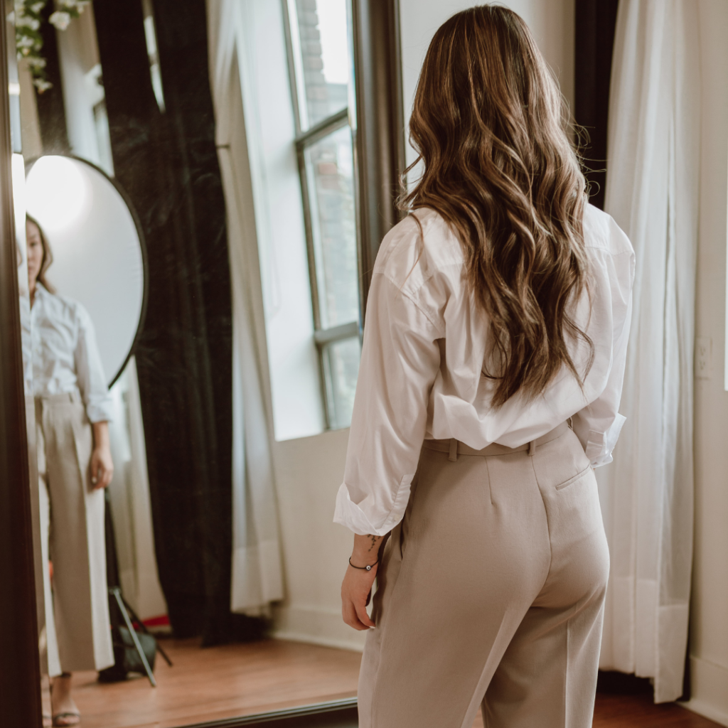 woman looking at reflection in mirror wearing business clothes