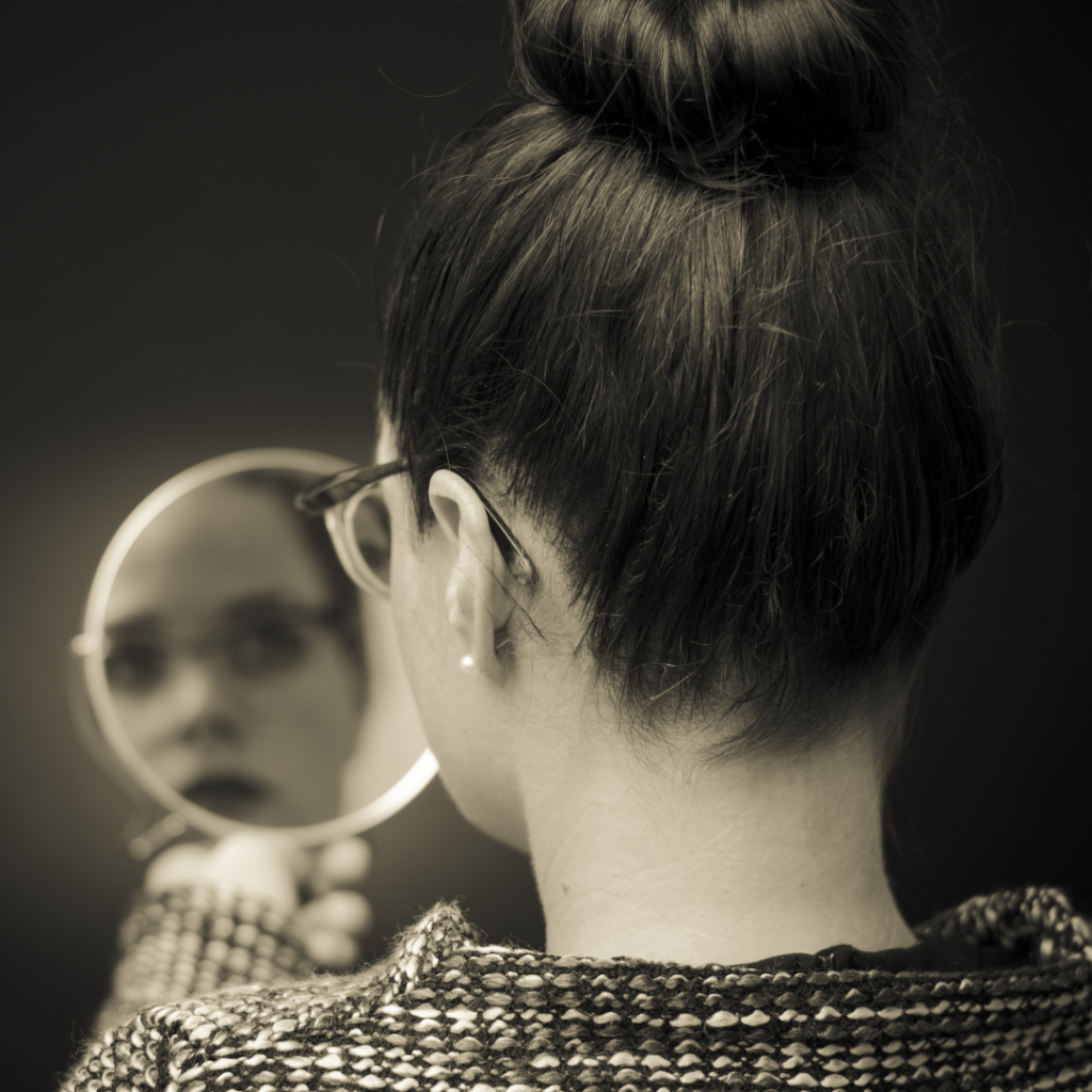 woman looking at self reflection in mirror