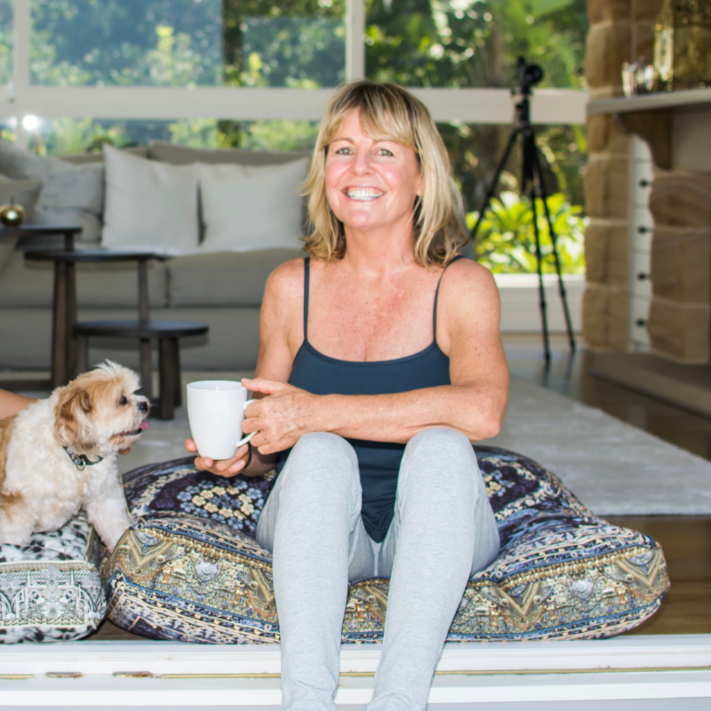 woman sitting next to dog with mug in hand