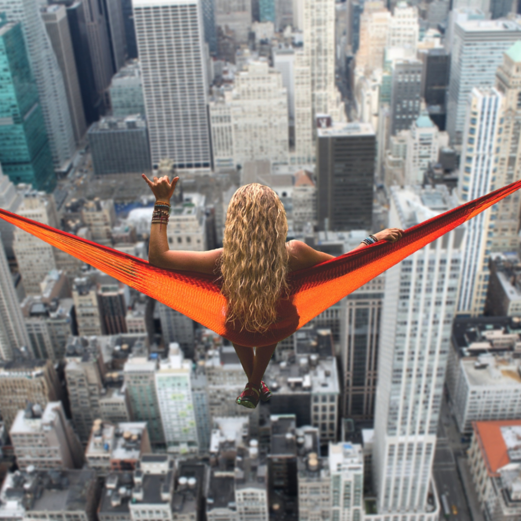 woman sitting in hammock above city skyscrapers