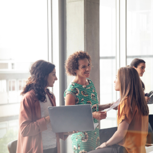 women with laptop and papers talking at an office