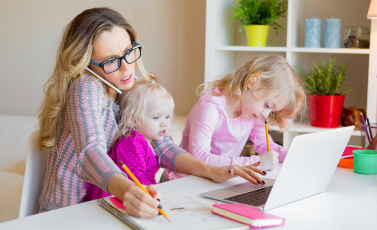 mom working on laptop and on the phone with two kids on lap