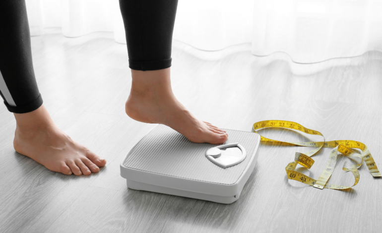 woman's feet stepping on scale with tape measure on floor