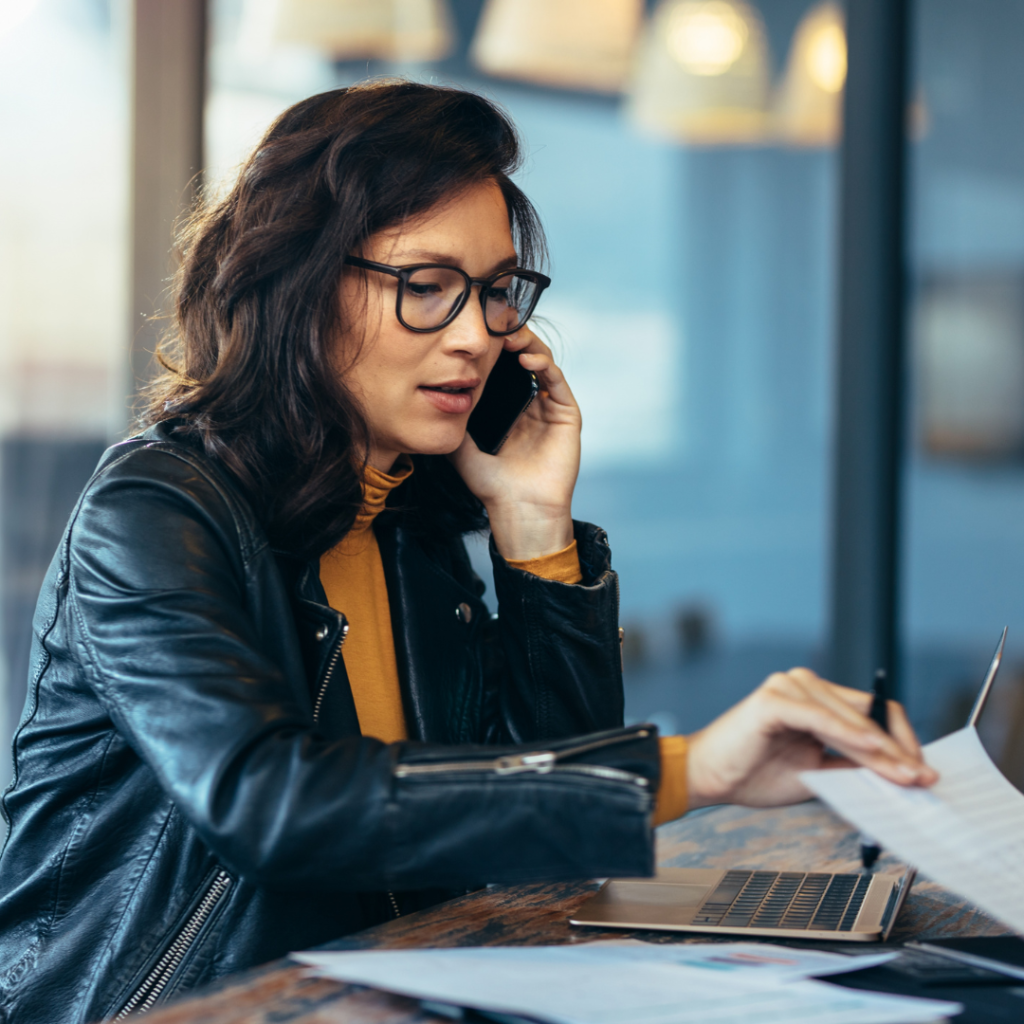 business woman on phone and shuffling through papers