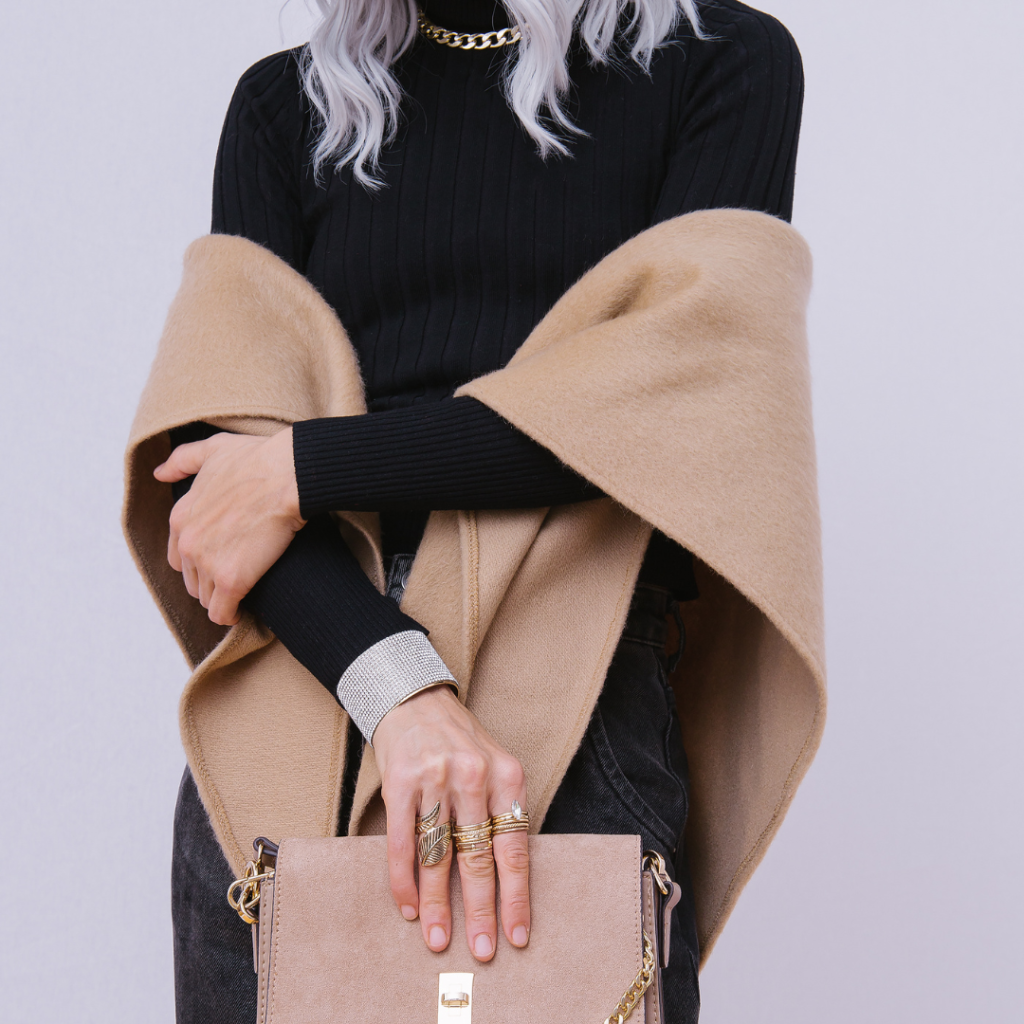 fall fashion model in black shirt with tan scarf wrapped around arms holding tan purse