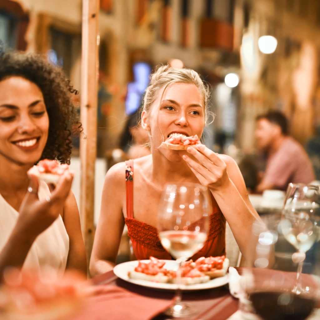 happy woman at dinner with friends eating bruschetta