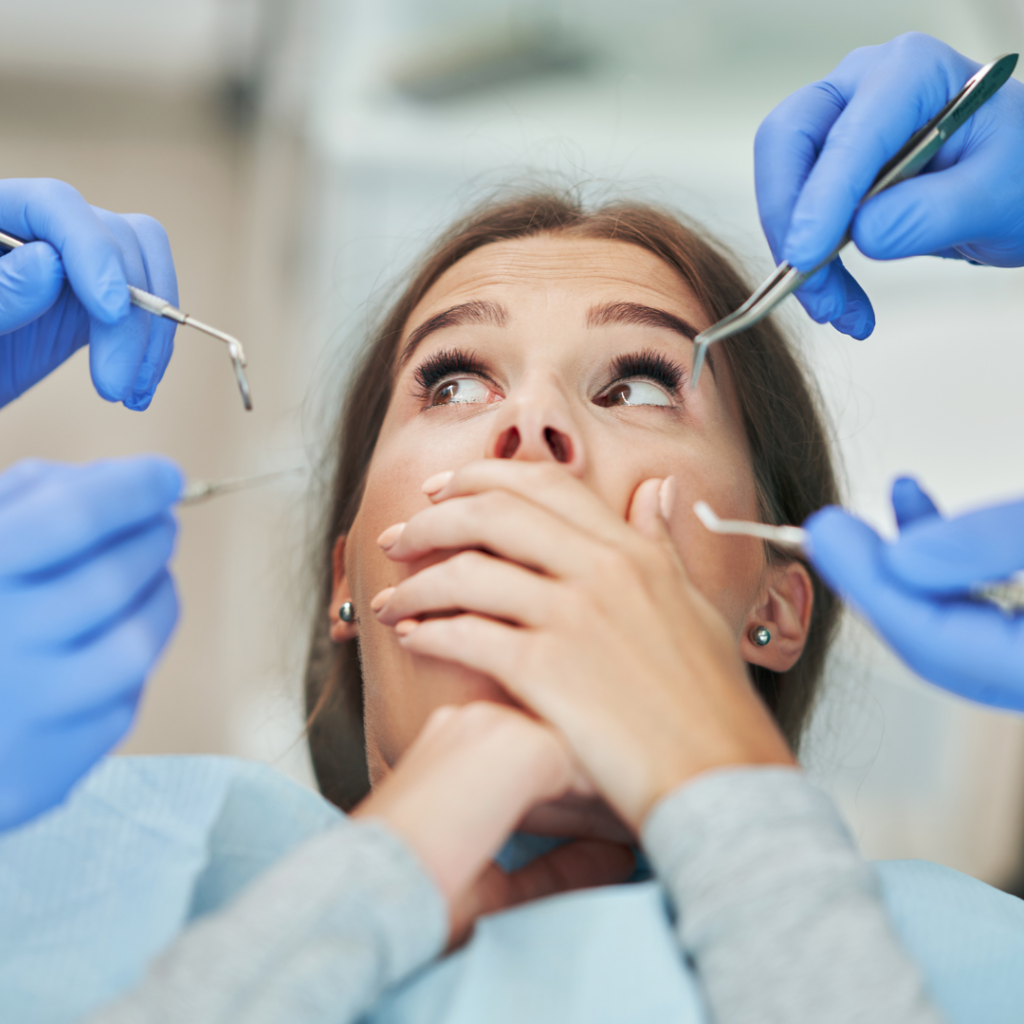 woman covering mouth at dentist with dentists holding tools