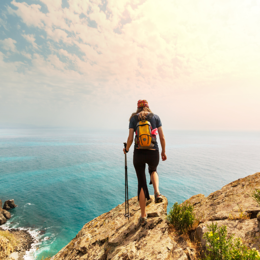 woman solo hiking looking at ocean over cliff