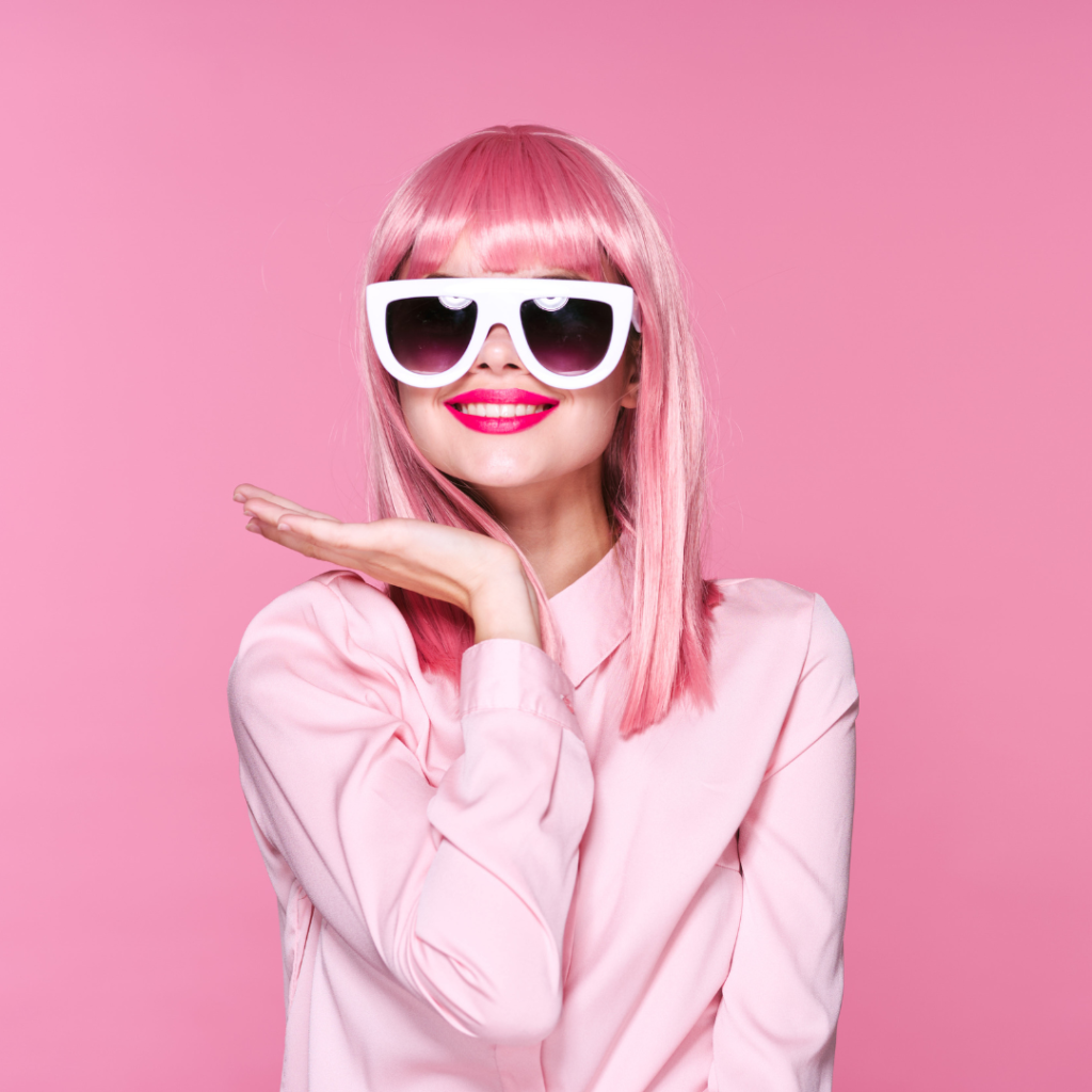 woman with pink hair wearing pink shirt and white sunglasses