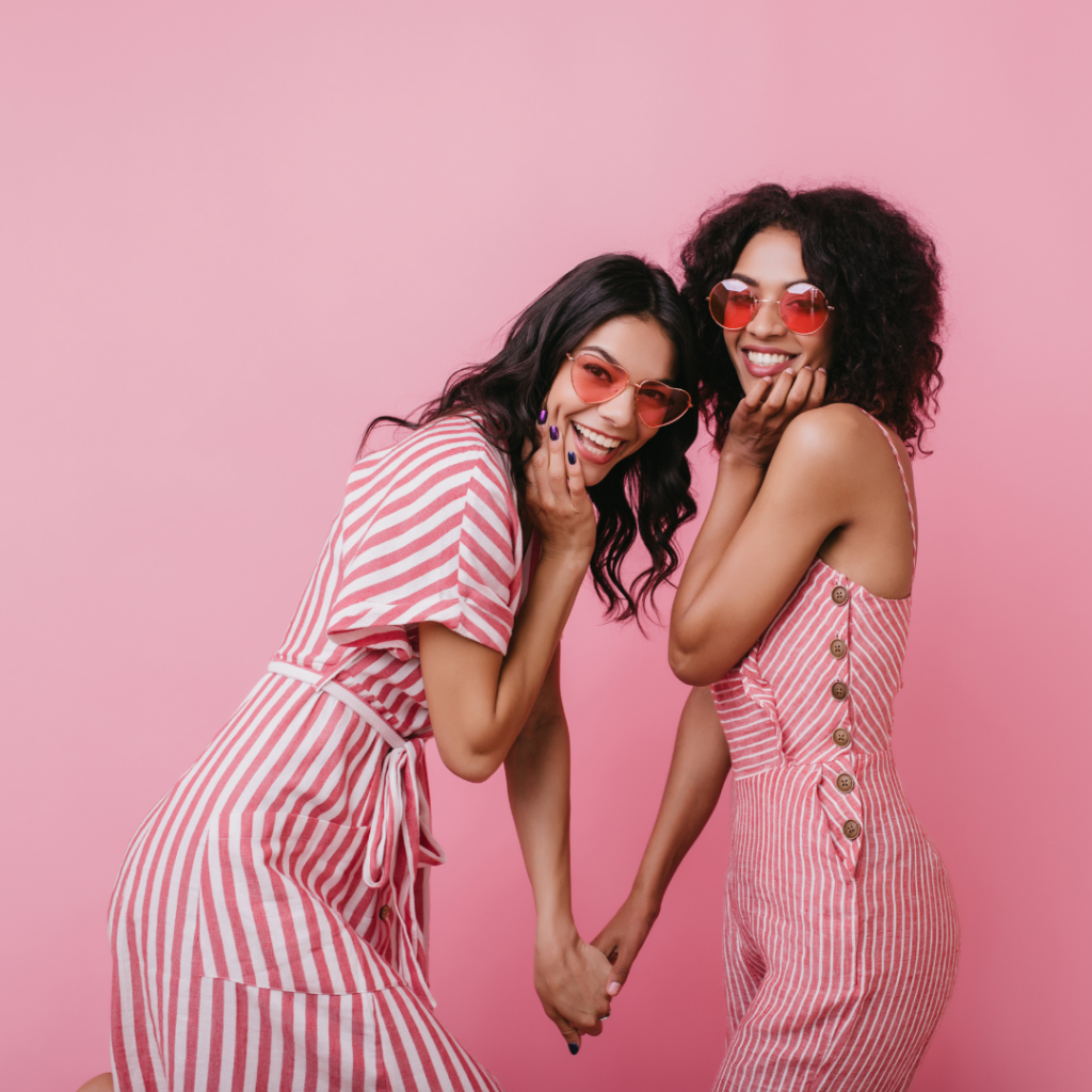 two women in pink holding hands and laughing