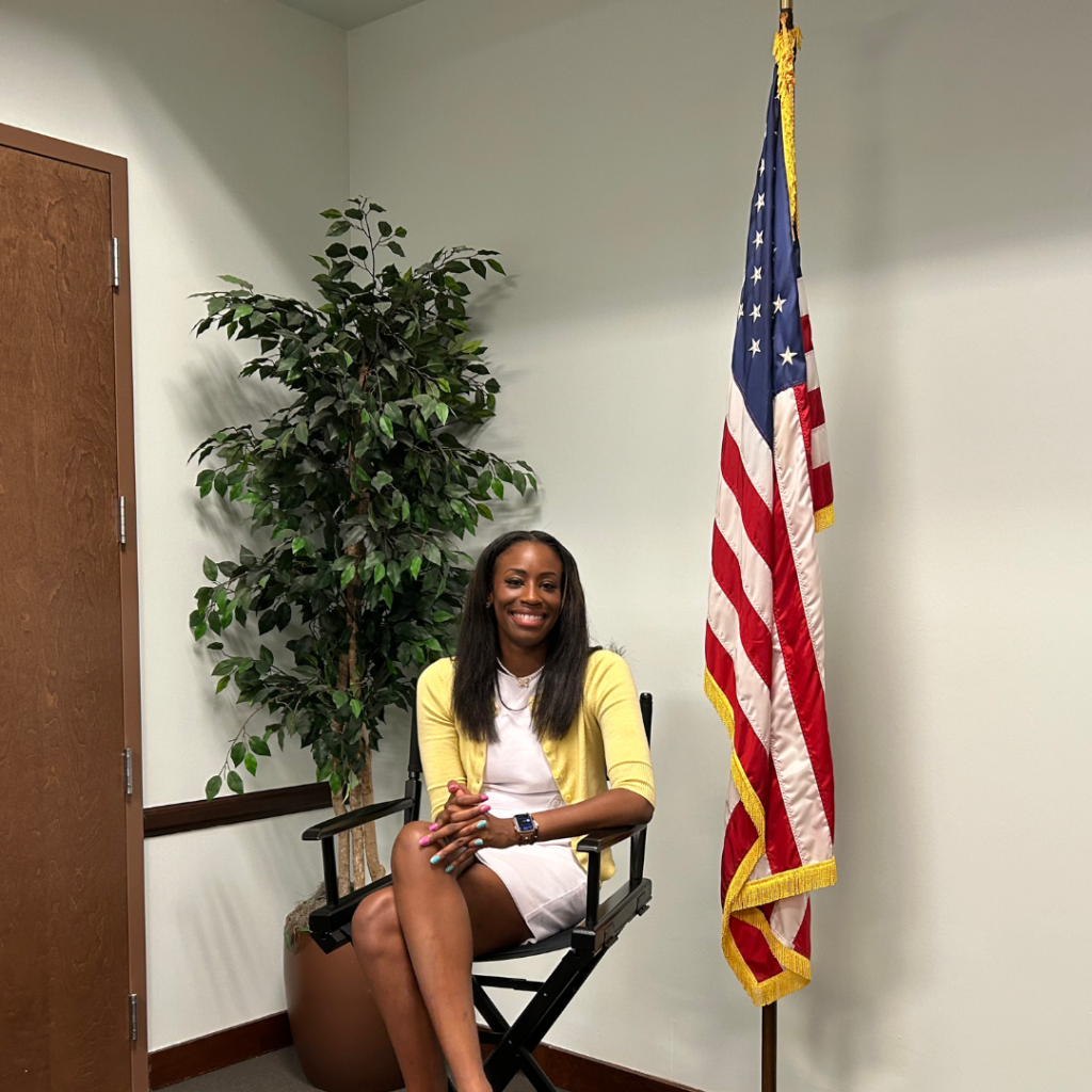 Rachelle sitting in chair next to American flag