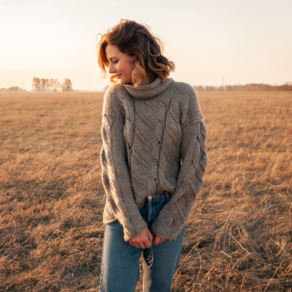 woman in big sweater standing in field