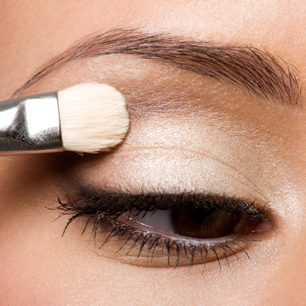 woman's eye with eyeshadow brush applying earthy toned makeup