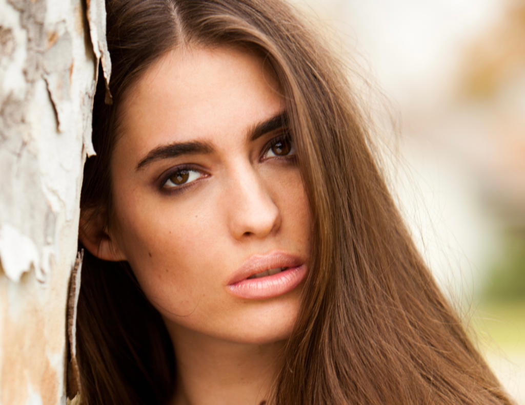 beautiful brunette leaning up on birch tree