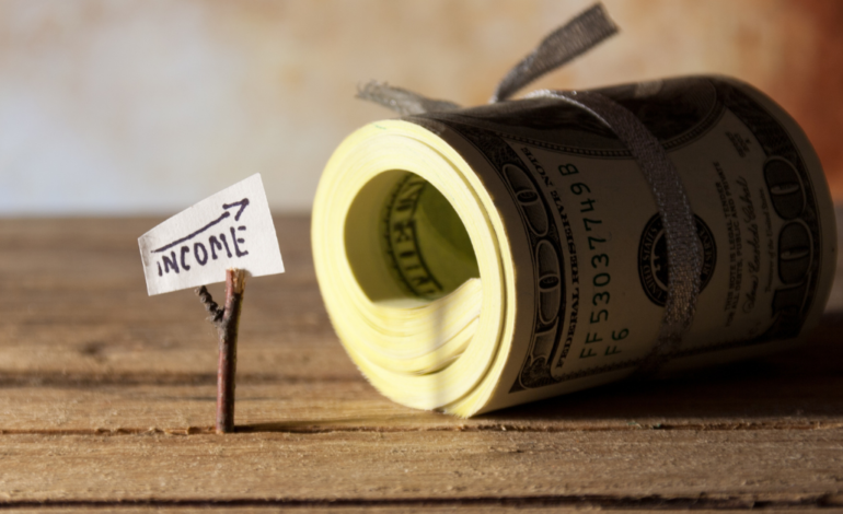 Income sign with arrow and rolled up stack of 100s