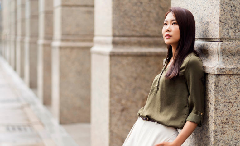 Asian Female in business outfit leaning on marble pillar