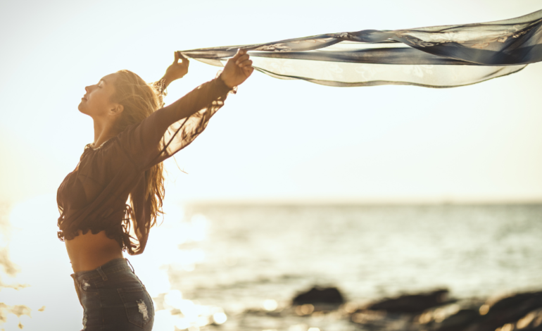 Female at beach with eyes closed and material blowing