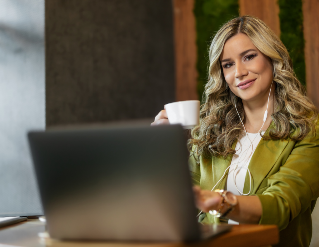 Woman in Green jacket with coffee using computer