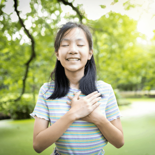 teen girl with eyes closed and hands on heart