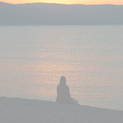Woman sitting on beach looking at sunset